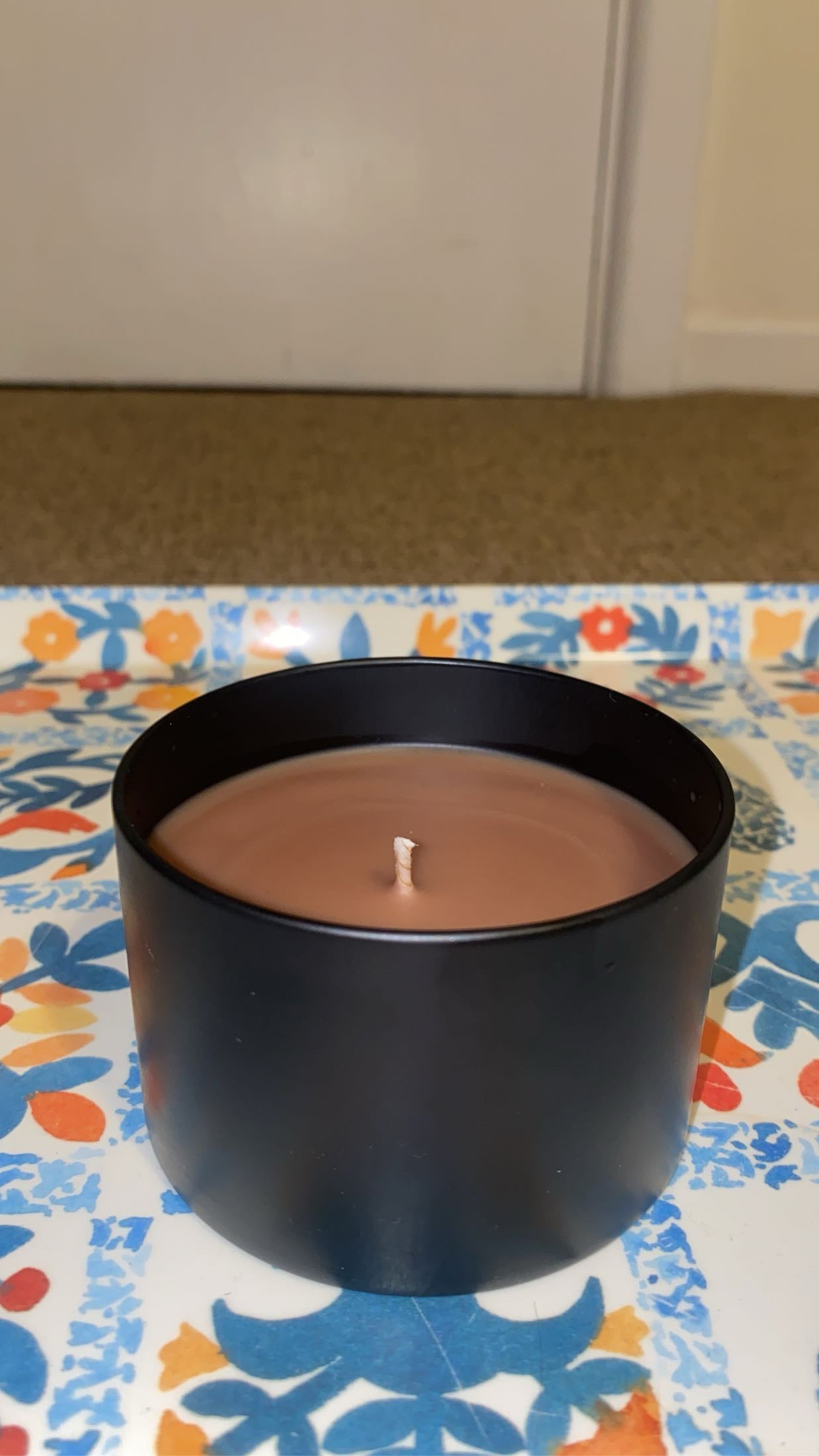 Black candle in a pot on a colorful tablecloth