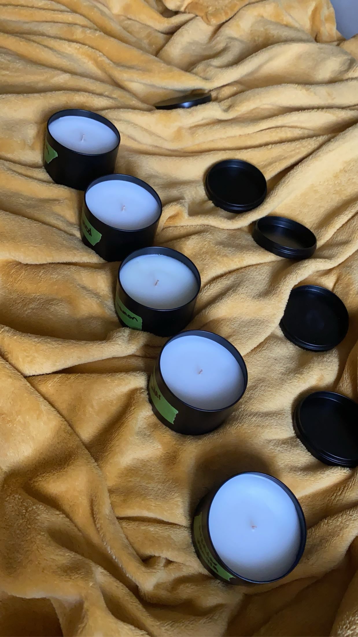 Candles with black lids on a beige fabric background