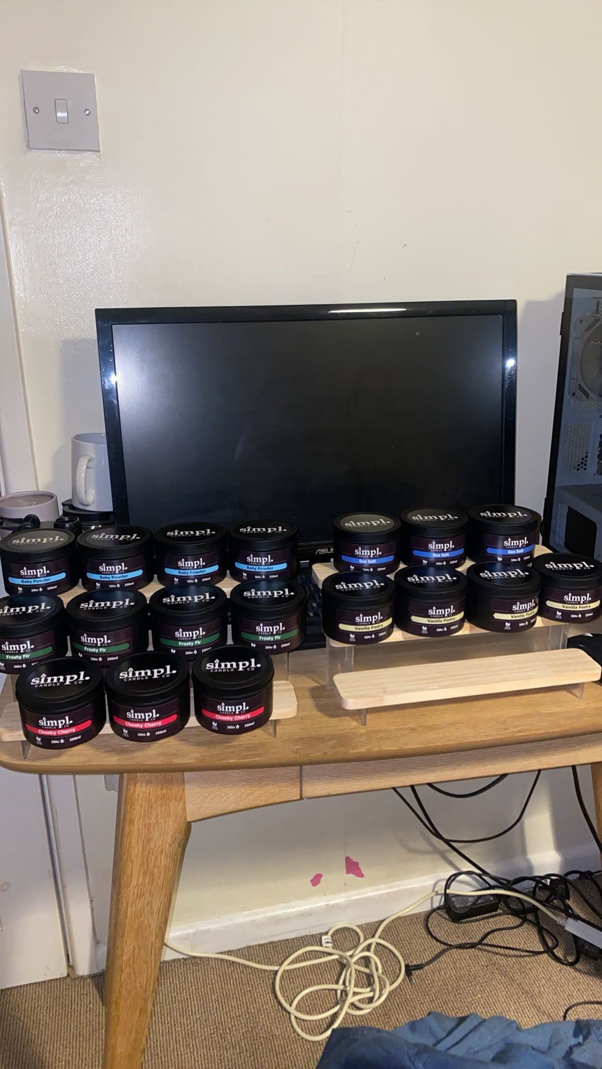 Multiple black containers with a brand logo on a wooden table in front of a television.